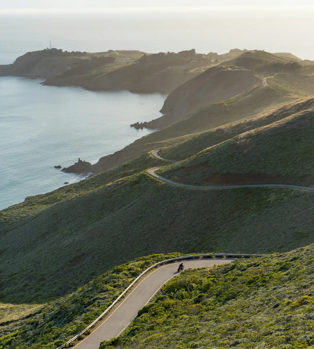 Photo by John Moeses Bauan on Unsplash Winding coastal road through green hills